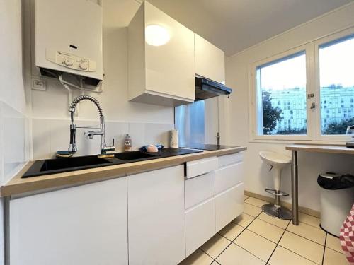 une cuisine avec des armoires blanches et un évier dans l'établissement Appartement Cosy Mérignac centre proche Tram, Parking, à Mérignac
