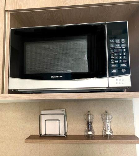 a microwave on a shelf in a kitchen at CASABONITA fte alberca, AirAc in Alpuyeca