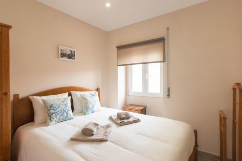 ein Schlafzimmer mit einem weißen Bett mit zwei Handtüchern darauf in der Unterkunft SaltWater Peniche Apartments in Peniche