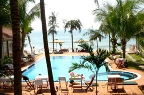 a swimming pool with palm trees and the ocean at Sunrise Resort in Mui Ne