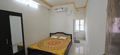 a small bedroom with a bed with a yellow comforter at Panihati Village in Pānihāti