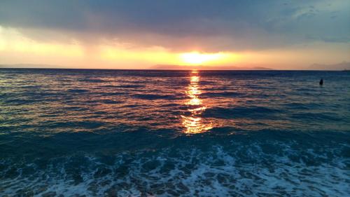 a sunset over the ocean with a person in the water at Family Stone House with Sea View and Parking - Pets welcome in Podgora