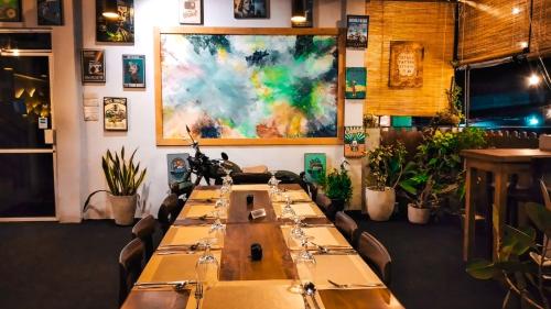 a long table in a restaurant with a painting on the wall at CITYSCAPE YALA BY 999 HOTEL & RESTAURANT in Tissamaharama