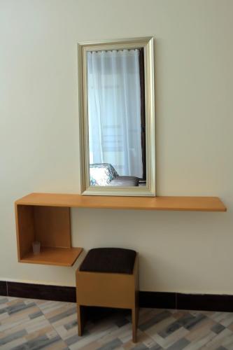 a mirror on a wall with a table and a stool at Daisy's Apartments in Entebbe