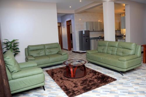 a living room with two green couches and a table at Daisy's Apartments in Entebbe