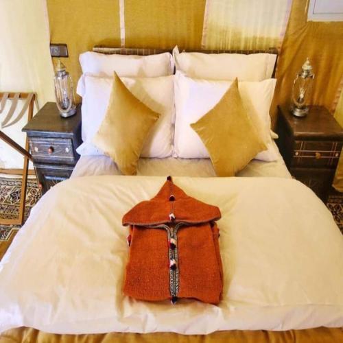 a white bed with a bag on top of it at Desert Paradise Luxury Camp in Merzouga