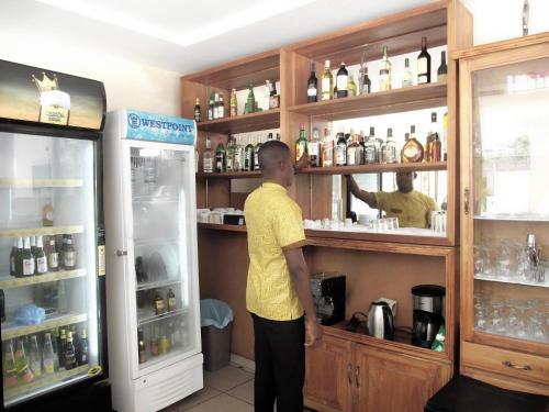 a man standing behind a counter in a bar at Hotel Ghis Palace in Baguida