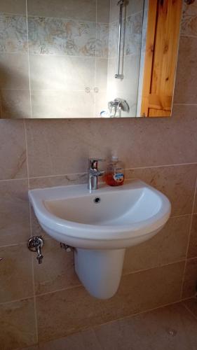 a white sink in a bathroom under a mirror at Xlendi Cozy Apartment in Xlendi