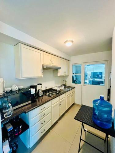 a kitchen with white cabinets and a table in it at Departamento la isla musala in Lima del Alto