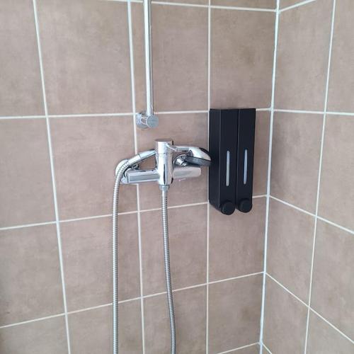 La salle de bains carrelée est pourvue d'une douche et d'un tuyau. dans l'établissement Appartement Brest Pilier Rouge, à Brest