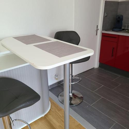 une table blanche avec deux chaises et une cuisine dans l'établissement Appartement Brest Pilier Rouge, à Brest