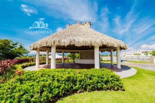 a gazebo with a straw roof on the grass at CASABONITA fte alberca, AirAc in Alpuyeca