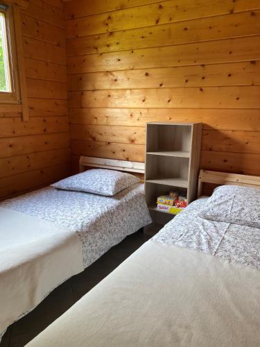 deux lits dans une chambre aux murs en bois dans l'établissement Chalet, à Parois