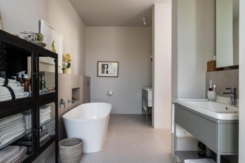 a bathroom with a large white tub and a sink at Romansbaai Collection in Gansbaai