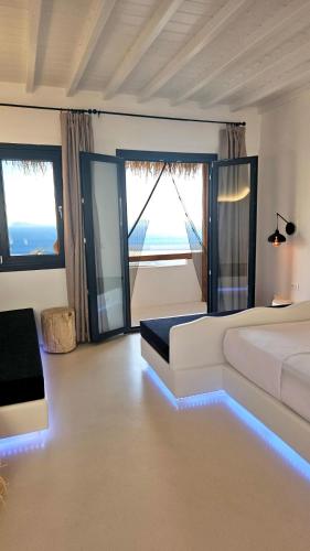 a bedroom with a white bed and large windows at ELLI TROPiCAL LUXURY SUITES SUNSET-INFINITY POOL- SEA SIDE-NEAR CENTER PARKING in Mikonos
