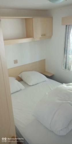 une chambre avec un lit blanc et une fenêtre dans l'établissement Mobil home place 26, à Villegusien Le Lac
