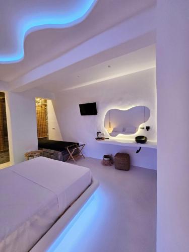 a white bedroom with a bed and a flat screen tv at ELLI TROPiCAL LUXURY SUITES SUNSET-INFINITY POOL- SEA SIDE-NEAR CENTER PARKING in Mikonos