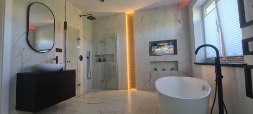 a bathroom with a tub and a sink and a mirror at Baltivia ADULTS ONLY in Świnoujście