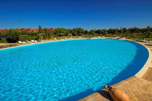 a large swimming pool with blue water in a resort at Oliva Hotel Condominium Marrakech in Marrakech