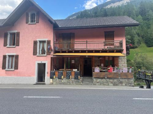 a pink house with people sitting on a balcony at Raccard rénové in Orsières
