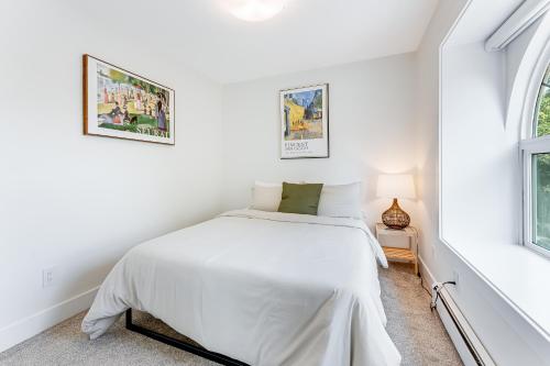 a white bedroom with a bed and two windows at Riley Park-Modern 4 Bedroom Home, Central location in Vancouver