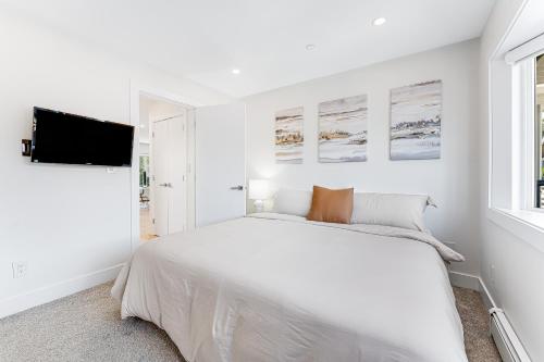 a white bedroom with a white bed and a window at Riley Park-Modern 4 Bedroom Home, Central location in Vancouver