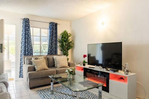 a living room with a couch and a flat screen tv at The Pearl I Near US Embassy, Stadium, 3Br 2Ba townhouse in Liguanea