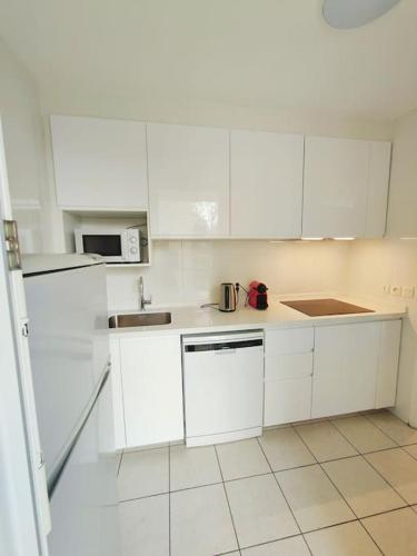 une cuisine blanche avec des armoires blanches et un évier dans l'établissement Appartement 2P à Ivry, aux portes de paris avec parking privé, à Ivry-sur-Seine