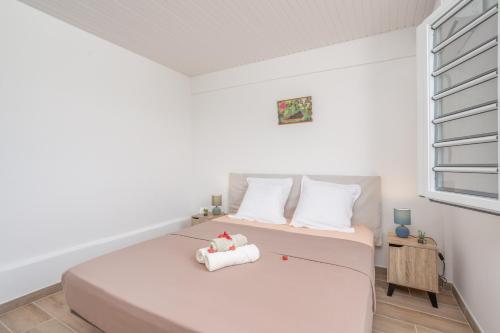 a bedroom with a bed with white sheets and a window at Maison Bel Colibri - Calme, Spacieux in Quartier la Monnerot