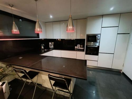 une cuisine avec des armoires blanches et un comptoir noir dans l'établissement Maison - Jacuzzi Jardin Parking proche Paris & CDG, à Drancy