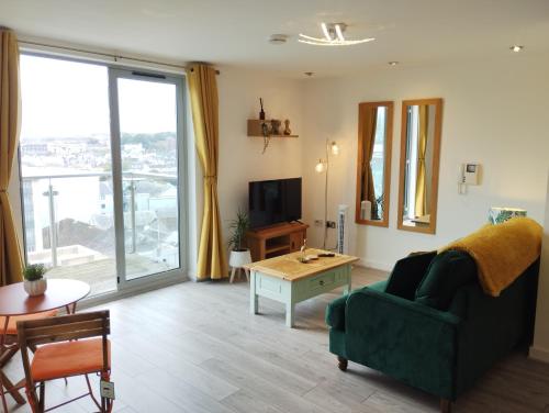 a living room with a green couch and a table at The Green Top flat with parking included amazing views and perfect location in Plymouth