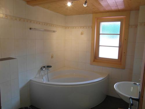 ein Badezimmer mit einer großen Badewanne und einem Waschbecken in der Unterkunft Les Promenades en Montagne in Chateau-d'Oex