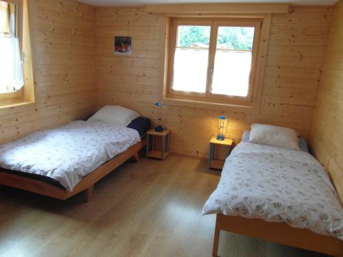 duas camas num quarto com duas janelas em Les Promenades en Montagne em Château-d'Oex