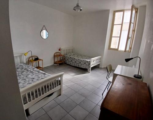 une chambre avec deux lits et un bureau et une fenêtre dans l'établissement Chez Anne-Laure, à Villeneuve-sur-Lot