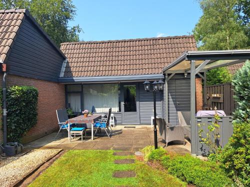 a house with a patio with a table and chairs at De groene oase de Boschberg in Biddinghuizen