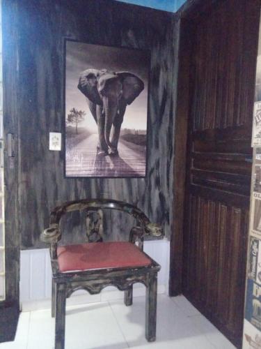 a painting of an elephant on a wall with a chair at Quarto refrigerado com cama de casal in Coxipó da Ponte