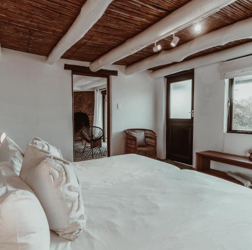 a bedroom with a large white bed and a mirror at Stanley Island in Plettenberg Bay