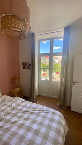 une chambre avec un lit et une grande fenêtre dans l'établissement Appartement centre de Vichy, à Vichy
