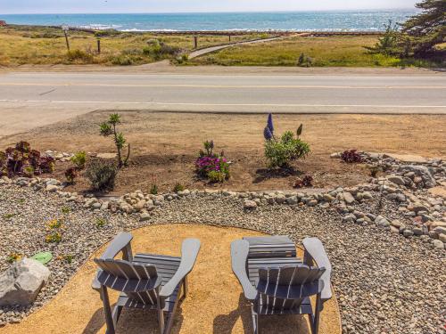 two chairs and a garden with a view of the ocean at Windrush Inn - Cambria in Cambria