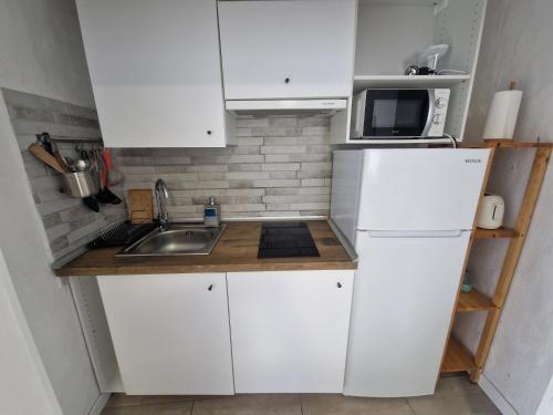 Una pequeña cocina con gabinetes blancos y un fregadero. en Casita Dorotea, en Sabinosa
