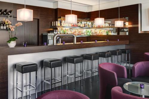 a bar in a restaurant with purple stools at IntercityHotel Hamburg Hauptbahnhof in Hamburg