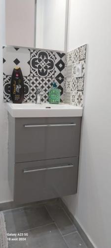 La salle de bains est pourvue d'un lavabo aux motifs noirs et blancs sur le mur. dans l'établissement Cosy T2 au centre historique de la ville Toulon, à Toulon