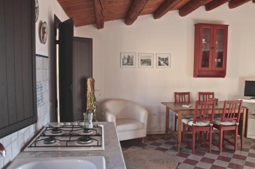 uma cozinha com um fogão e uma mesa com cadeiras em Carruggiu Casavacanze em Caltagirone