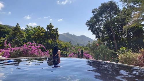 a woman standing on top of a swimming pool with flowers at Villa La Fortuna B&B Altos del Maria in Filipina