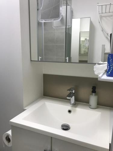 un lavabo blanc dans une salle de bain avec un miroir dans l'établissement 1 Next To Paris, à Montreuil