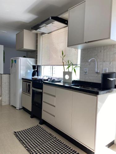 a kitchen with white cabinets and a white refrigerator at Apartamento no centro girassol 05 in Foz do Iguaçu