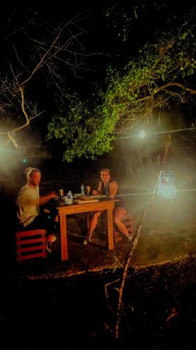 two people sitting at a picnic table at night at River paradise safari house with cooking class in Udawalawe