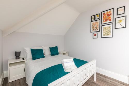 a white bedroom with a white bed with blue pillows at Dove Court Travel Lodge 7 - Top Floor Double Bedroom in Bristol