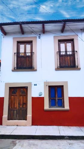 a white and red house with two doors and two windows at Linda casa azul ubicada en el corazón de Pátzcuaro in Pátzcuaro