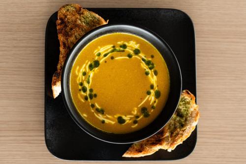 a black plate with a bowl of soup and some bread at Hotel Jökull in Höfn